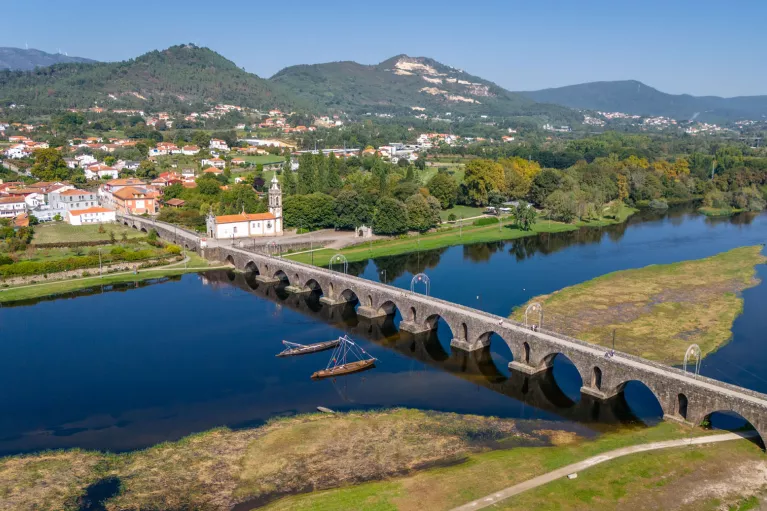 Long stone bridge with a river underneath, leading to a small town
