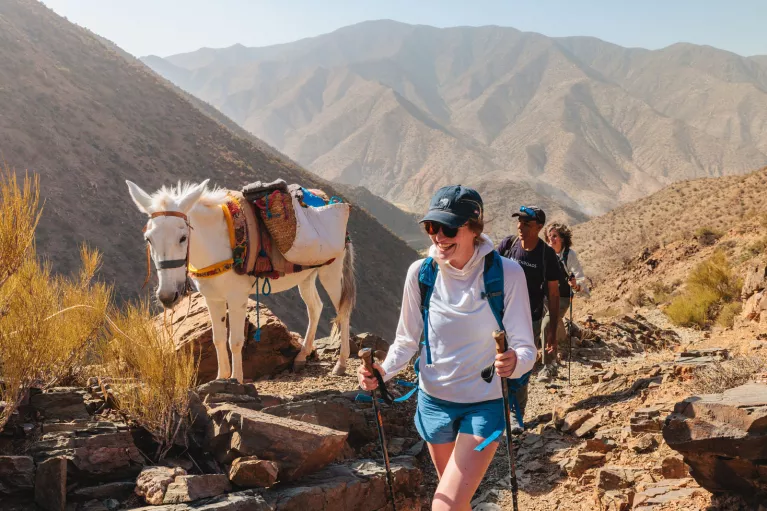 Group of people smiling while hiking next to a white horse