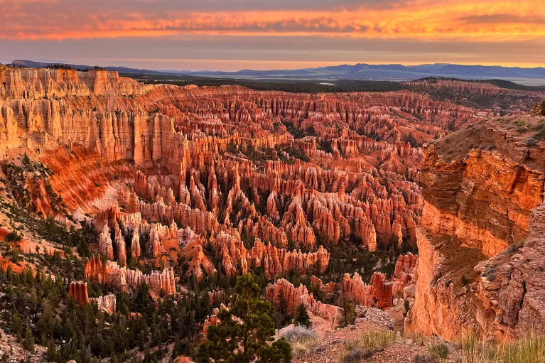 Sky view of a valley of orange canyons with the sunset in the distance