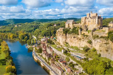 Castle-like building on top of a hill, with a river on the ground floor