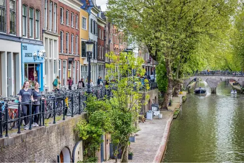 Canal with boats riding through, with a row of hotel buildings to the left