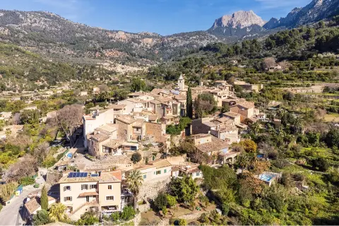 Small town of beige, stone buildings surrounded by a grassy valley