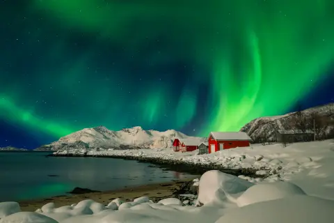 Aurora over a snowy field with two red barns