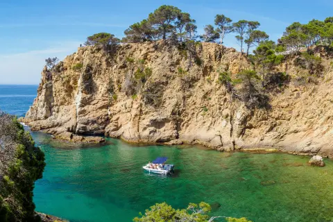Large cliffs by the ocean shore, with a boat floating in the water