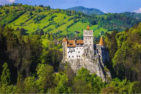 Castle on top of a cliff, surrounded by tall hills and grassy fields