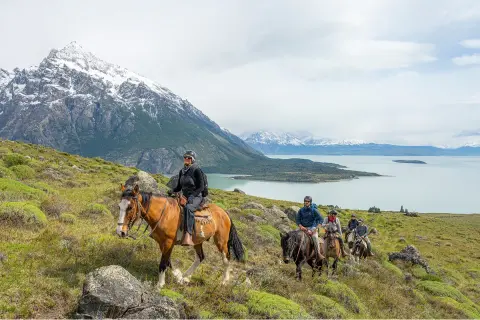 Group of people horseback riding with a large lake in the distance