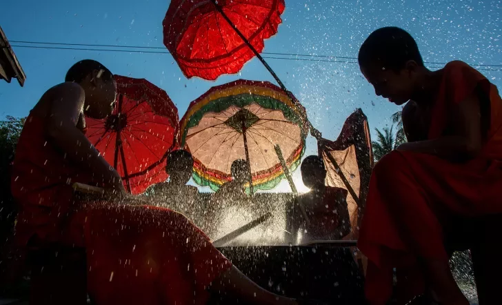 novice monks beating a new dry with palm reeds and splashing water