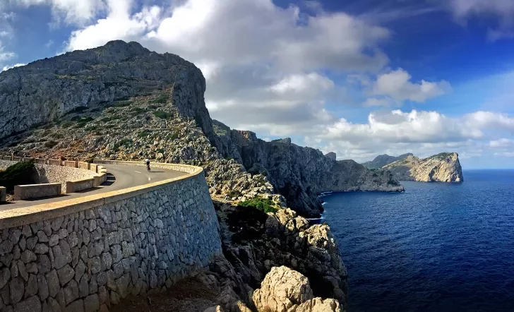 Biker going around a curve on an elevated road on the coast of Mallorca.