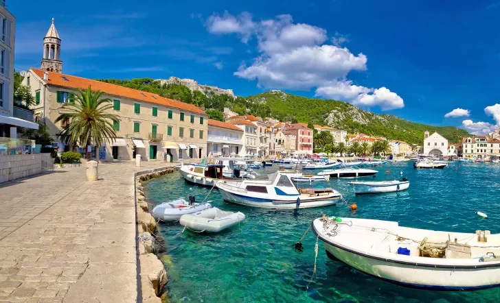 Wide shot of Croatian coastal town, boats, blue water, hills, etc.