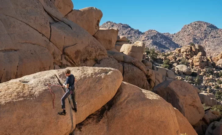 Guest rock climbing with desert vista behind them.