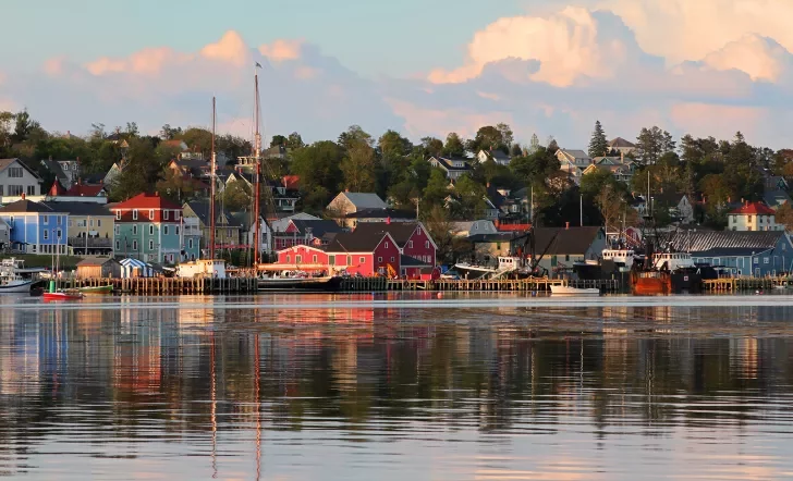 Wide shot of seaside town at sunset, vibrant red houses scattered throughout.