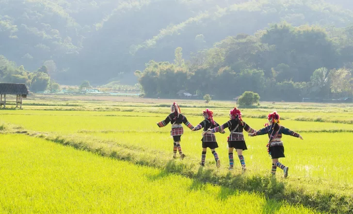 Thai people in traditional clothes running through a green field