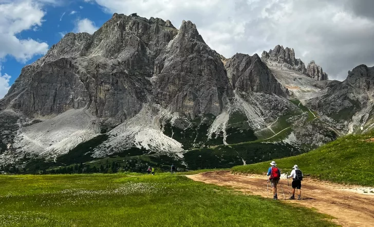 Two guests on trail, hiking towards large mountain in front of them.