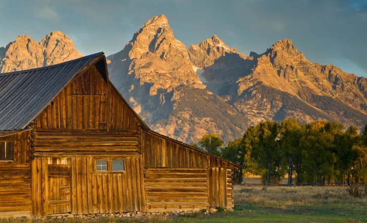 Wooden cabin with rocky mountains in background