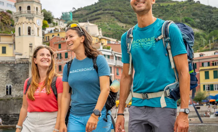 Two women and one man smiling while walking on a boat dock by the water