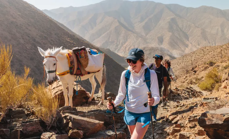 Group of people smiling while hiking next to a white horse