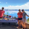 Three guests next to lunch table, large lake in background.