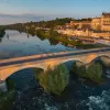 Bird's eye shot of cyclists over Loire River during sunset.  Château Royal d'Amboise behind.