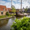 Shot of small river, houses, wooden boat.