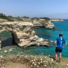 Guest overlooking white-rock coast, light blue water in background.
