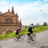 Cyclists riding along an Italian road with an old church building