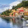 Wide shot of Lake Como coastline, colorful houses.