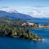 Wide shot of inlet, white building, snowy peak, larger lake in distance.