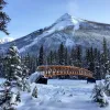 Wide shot of snowy bridge, Rockies in background.