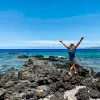 Woman walking towards the ocean with her arms in the air