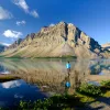 Wide shot of large lake, guest looking towards craggy mountains.
