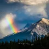 Shot of mountain range, clouds, rainbow visible.