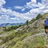 Guest hiking on craggy hillside, cloudy sky behind them.