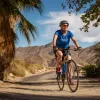 Guest cycling past palm tree, desert landscape behind him.