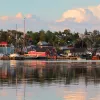 Wide shot of seaside town at sunset, vibrant red houses scattered throughout.