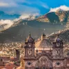 Wide shot of South American city, mountain range in distance, large cathedral in foreground. 