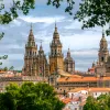 POV shot of Cathedral of Santiago de Compostela, taken from distant treeline.