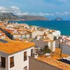 Shot of coastal town, white and tan houses, ocean.