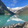 Wide shot of blue lake, mountains, clouds, sky.