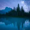 Lake, mountain, forest, vibrant nighttime vista.