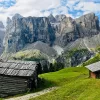 Shot of two old, wooden houses, angular cliffs in distance.