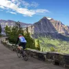 Man riding a bike on a windy road with a mountain in the distance
