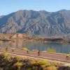 people biking down a road by a mountain range