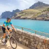 Man biking on a stone path looking out to a lake and a small town