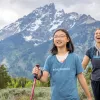 Woman and girl with walking poles hiking in a grassy valley