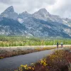 Three people biking with the Tetons in the background