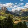green mountains and lakes below a blue sky with white fluffy clouds