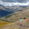Woman with walking poles descending down a dirt hill covered with rocks