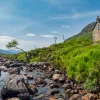 Boulders scattered through a river with a house on top of a small hill