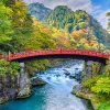 Red bridge over an active river, with large mountains in the background