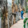 Woman standing on a wooden bridge, between two large cliffs
